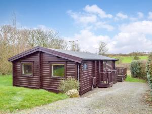 a wooden cabin in a field with a driveway at Cwm Gain in Llanrian