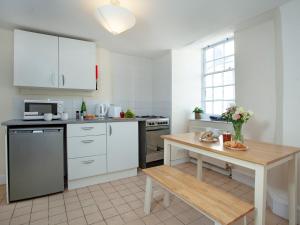 a kitchen with white cabinets and a wooden table at Bridgetown in Totnes