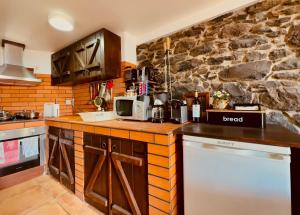 eine Küche mit einer Theke und einer Steinmauer in der Unterkunft Madeira Inn The Typical House in Calheta