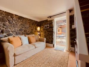 een woonkamer met een bank en een stenen muur bij Madeira Inn The Typical House in Calheta