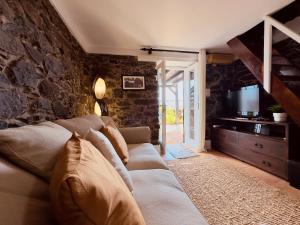 een woonkamer met een bank en een televisie bij Madeira Inn The Typical House in Calheta