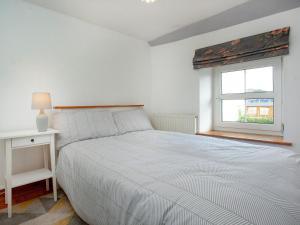 a white bedroom with a bed and a window at Summer Cottage in Bideford