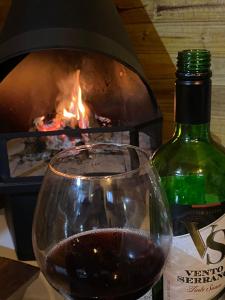 a glass of red wine next to a fireplace at Pousada Vó Ciloca in Praia Grande