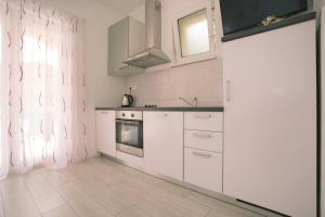 a white kitchen with white cabinets and a window at Apartments with a parking space Kastel Kambelovac, Kastela - 21071 in Kaštela