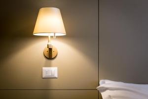 a lamp on a wall next to a bed at Mirtillo Blu Family Apartment in Alagna Valsesia