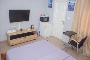 um quarto com uma cama, uma televisão e uma cadeira em Studio cosy et moderne em Lomé