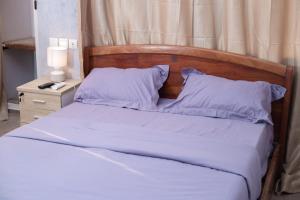 a bed with white sheets and a wooden headboard at Studio cosy et moderne in Lomé