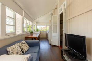 een woonkamer met een blauwe bank en een flatscreen-tv bij Quaint & Cosy 1 Bedroom Apartment in Queenslander. in Brisbane