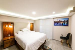 a bedroom with a large white bed and a chair at Rochester 10 in Mexico City