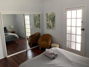 a bedroom with a bed and a chair and a mirror at Charming 1920's 4Br freestanding Plantation Qldr. in Brisbane