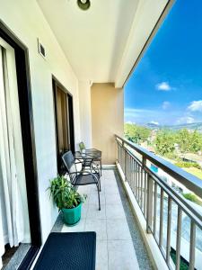 einen Balkon mit 2 Stühlen und einem Tisch in der Unterkunft The Oak Smart Suite 2BR Baguio in Baguio City