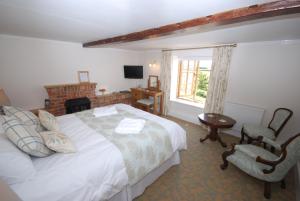 a hotel room with a bed, chair, and nightstand at The Chequers Inn in Rookley