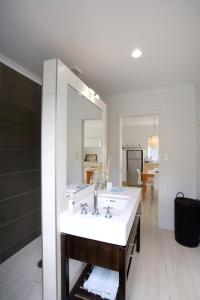 a white bathroom with a sink and a mirror at Bach on Burrell in Oneroa