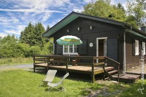 ein kleines Haus mit einer Terrasse und einem Sonnenschirm in der Unterkunft Spacious Chalet with Private Garden in Waimes in Sourbrodt