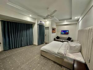a bedroom with a large bed and a couch at MUDAN hotel and suite in Islamabad