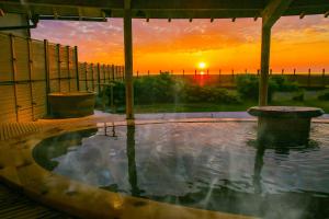 uma piscina de água com um pôr-do-sol ao fundo em Ooedo Onsen Monogatari Premium Shiomiso em Murakami