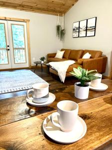 una sala de estar con 2 tazas de café sobre una mesa de madera en Almost Heaven Mountain Cabin, en Murphy