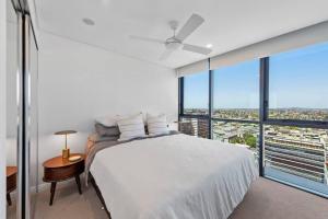 a bedroom with a white bed and large windows at Prime Located Luxe 2 BR Sky Home/Sensational Views in Brisbane +21 photos