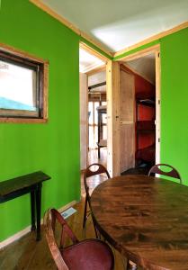 zielony pokój z drewnianym stołem i krzesłami w obiekcie Lost River Hostel w mieście French Lick