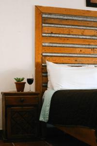a bed with a wooden headboard and a glass of wine at Kay Apartments Isla Mujeres in Isla Mujeres