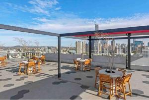 New 3 Bed Penthouse Resort style complex في بريزبين: فناء به طاولات وكراسي على السطح