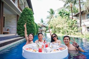 um grupo de pessoas em uma piscina com uma mesa na água em Grand Whiz Hotel Nusa Dua Bali em Nusa Dua