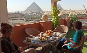 Giza的住宿－Grand Pyramids In，两个女人坐在桌子上,拿着食物和金字塔