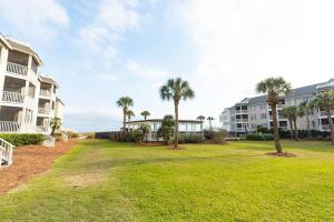 a yard with palm trees in front of condos at Tidewater I102 - Beautiful Oceanview! First Floor Walkout! in Isle of Palms