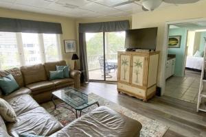 sala de estar con sofá y TV en Port O' Call C302 - IOP Island Retreat! Treetop Oceanview!, en Isle of Palms
