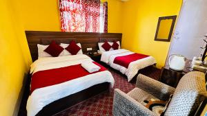two beds in a room with yellow walls at Hotel Pathibhara in Tāplejung