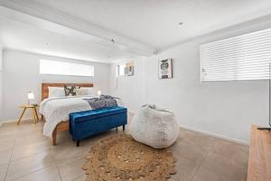 a bedroom with a bed and a blue ottoman at Charming 5BR Family Home w/Pool 10min from Airport in Brisbane