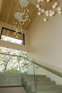 a staircase with a chandelier and a glass railing at Casa Kaiman - Apartment Vista in Nosara
