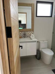 a bathroom with a toilet and a sink and a mirror at Casa Kaiman - Apartment Vista in Nosara