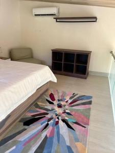 Dormitorio con cama y alfombra colorida en el suelo en Casa Kaiman - Apartment Vista, en Nosara
