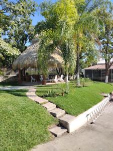 un edificio con una cabaña de paja con un banco y palmeras en Casas Real Imperio Blue, en Xochitepec
