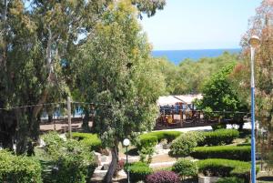 un jardin avec un train au loin planté d'arbres et de buissons dans l'établissement Pyrassos, à Nea Anchialos