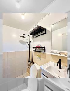 a bathroom with a sink and a toilet and a mirror at The Red Room 2bed room Condo in Imus