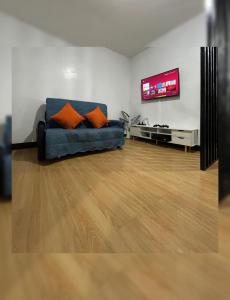 un soggiorno con divano blu e TV a schermo piatto di The Red Room 2bed room Condo a Imus