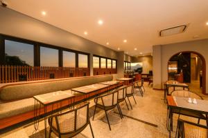 a restaurant with tables and chairs and windows at Nata Azana Hotel Solo in Solo