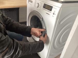 osoba kładzie pralkę w kuchni w obiekcie Holiday home Sydals XXXIX w mieście Høruphav