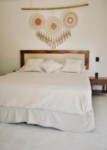 Una cama con sábanas blancas y almohadas en un dormitorio en Casa Luni, en Puerto Escondido