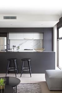 a kitchen with black and white cabinets and stools at Opera Apartments South Brisbane in Brisbane