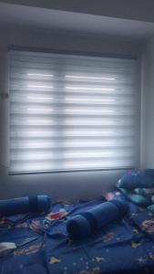 um quarto com uma janela com um cobertor azul numa cama em Watanabe Condo Unit em Pasong Bayog