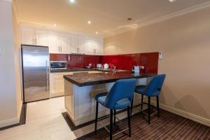 a kitchen with a refrigerator and two blue bar stools at Apartment 2, 9 River Lane Mannum in Mannum