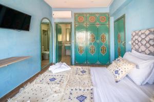 a bedroom with a bed and a bathroom with green doors at Riad Les Nuits De Fès in Fez
