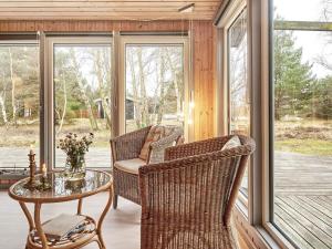 a screened in porch with wicker chairs and a table at Holiday home Aakirkeby XLIV in Vester Sømarken