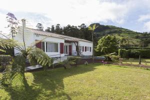 a white house with a palm tree in a yard at Lake View House in Sete Cidades
