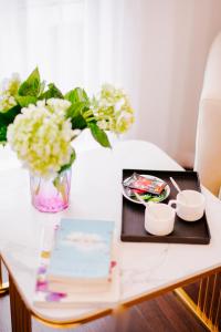 una mesa con una bandeja de comida y un jarrón de flores en Royal Lotus Hotel, en Hanói