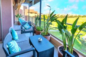 un balcon avec des chaises, des tables et des plantes en pot dans l'établissement Cozy Golf Apartment Wifi 4k-TV Netflix, à Marrakech