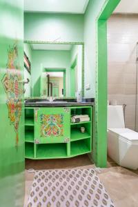 Baño verde con aseo y espejo en Riad Les Nuits De Fès, en Fez